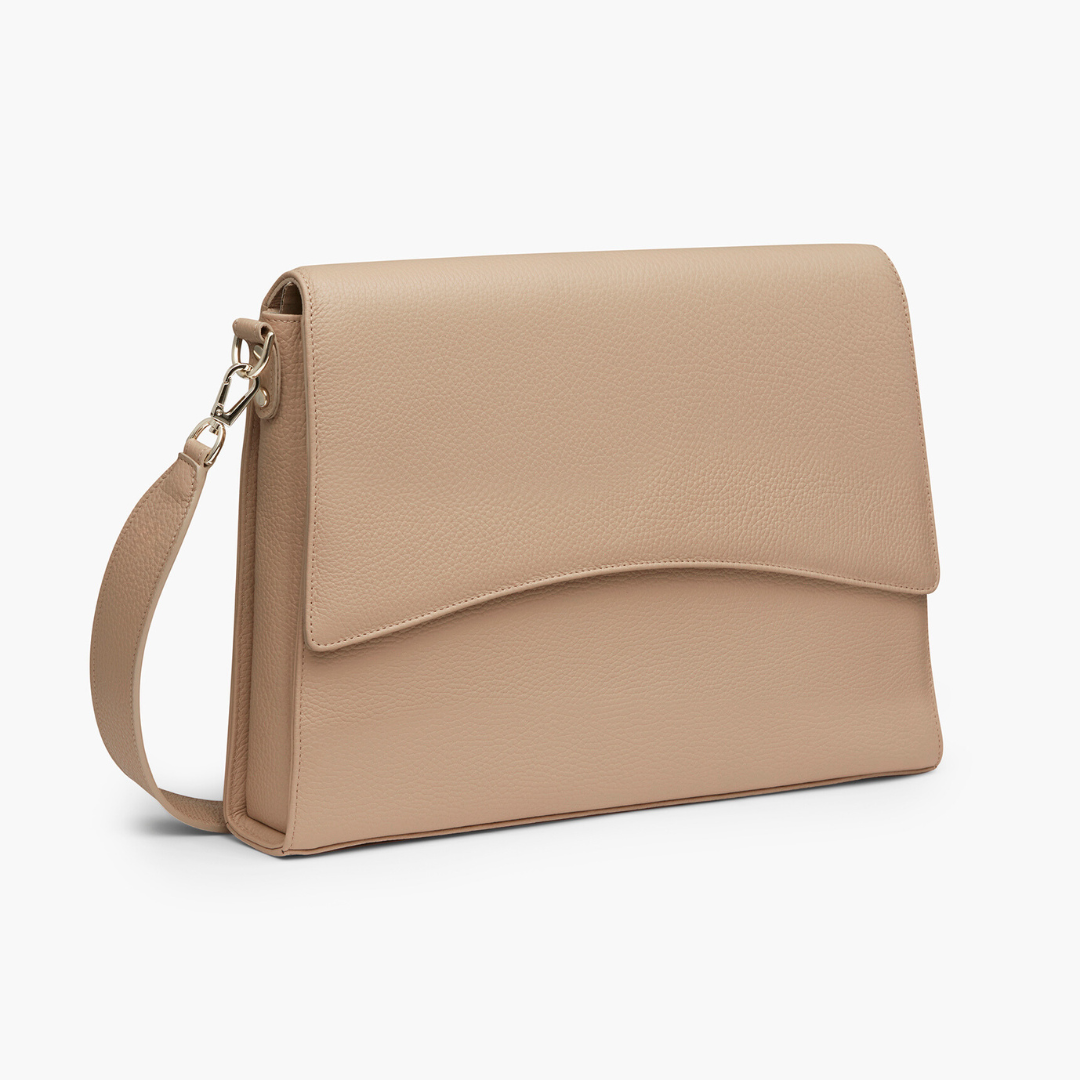 A beige laptop bag with grained leather and light gold metalware. It has a detachable shoulder strap. 